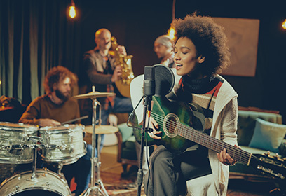 Young female playing guitar and singing in a band.