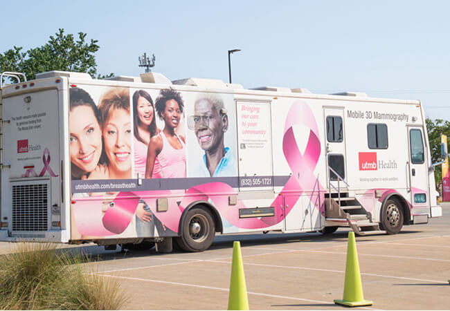 Large bus with breast cancer ribbon on the side.