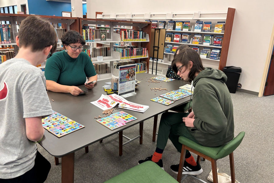 Outreach coordinator with two students in library