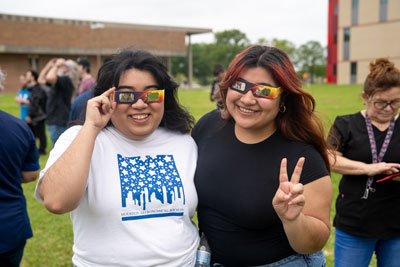 Students outside with solar eclipse glasses.